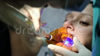 助手用牙科聚合紫外线灯照射病人牙齿特写。看牙医